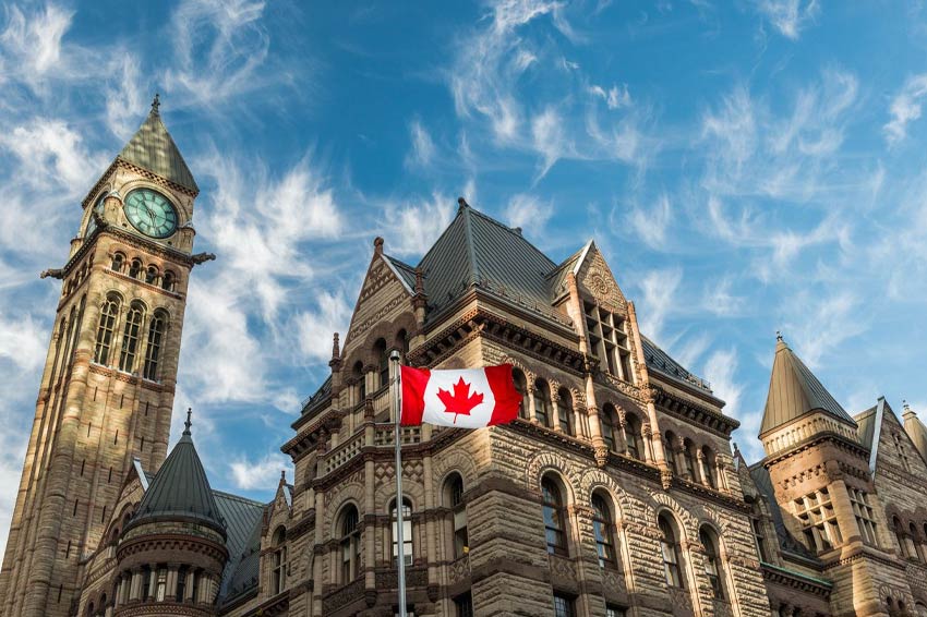 Canadian flag waves in front of historic building