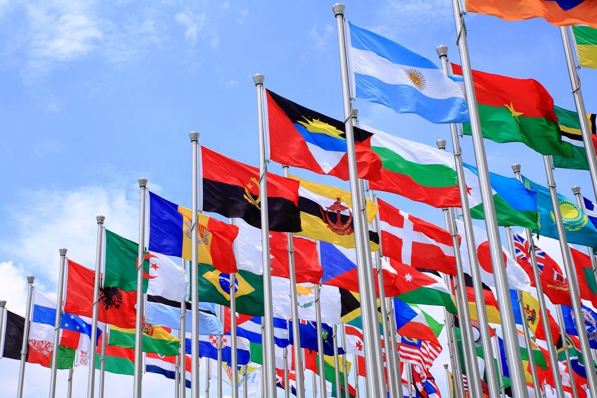Large grouping of international flags on flagpoles waving outside