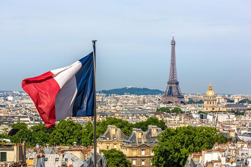 National flag of France flies near the Eiffel Tower in Paris, France