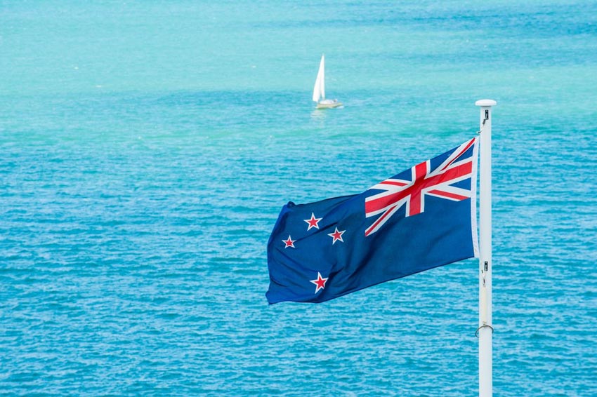 New Zealand flag waving in foreground from the ocean