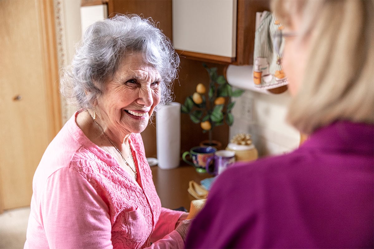 Senior Woman smiling in kitchen with Caregiver